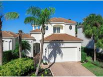 Two-story home with tile roof, white exterior, and lush landscaping at 1906 Harbour Links Cir # 14, Longboat Key, FL 34228