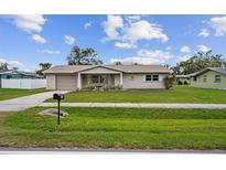 Tan single story house with a neatly landscaped lawn and driveway at 1215 E Venice Ave, Venice, FL 34285