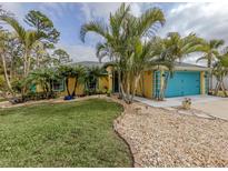 Bright yellow house with teal garage door, landscaping, and palm trees at 3972 Titan St, North Port, FL 34286