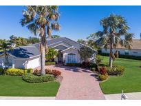 Single-Gathering home with paver driveway, lush landscaping, and palm trees at 9441 Cedar Ridge Ln, Sarasota, FL 34238