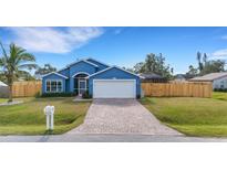 Beautiful blue house with a brick driveway, wooden fence, and lush lawn at 305 Coral Rd, Venice, FL 34293