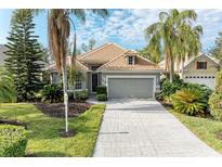 Single-story house with tile roof, gray garage door, and landscaped yard at 6710 Pebble Beach Way, Lakewood Ranch, FL 34202