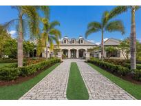 Elegant home with a stone driveway, lush landscaping, and palm trees at 8388 Catamaran Cir, Lakewood Ranch, FL 34202