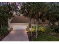 Brick driveway leads to a single-story home with a large garage, surrounded by lush landscaping at 1225 S View Dr, Sarasota, FL 34242