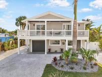 Two-story house with a white balcony, gray siding, and landscaped yard at 203 72Nd St, Holmes Beach, FL 34217