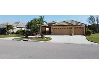 Tan three-car garage house with tile roof, manicured lawn, and palm trees at 3001 Seasons Blvd, Sarasota, FL 34240