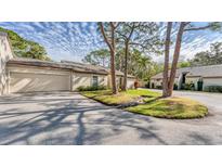 Exterior view of a charming villa with a two-car garage and lush landscaping at 4372 Woodmans Chart # 143, Sarasota, FL 34235