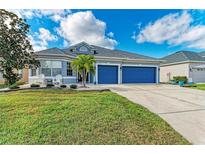 Two-story house with blue garage doors and well-manicured lawn at 12219 23Rd E St, Parrish, FL 34219