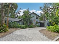 Two-story house with gray siding, paver driveway, and lush landscaping at 1702 Spoonbill Dr, Nokomis, FL 34275