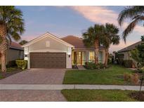 Single-story home with brown garage door, landscaping, and palm trees at 19256 Jalisca St, Venice, FL 34293