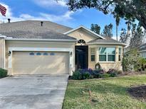 Tan house with gray roof, two-car garage, and landscaped front yard at 3312 92Nd E Ave, Parrish, FL 34219