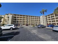 Multi-story condo complex with multiple balconies and parking lot featuring various parked cars on a sunny day at 3682 Lake Bayshore Dr # K402, Bradenton, FL 34205