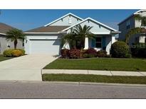 Single-story home with light blue exterior, landscaping, and a two-car garage at 4629 Garden Arbor Way, Bradenton, FL 34203