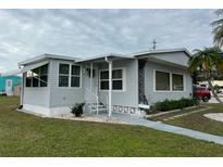 Single-wide manufactured home with gray siding, steps, and landscaping at 5327 Glen Echo Ave, Sarasota, FL 34234