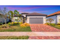 Single-story home with gray garage door and brick driveway at 7432 Summerland Cv, Lakewood Ranch, FL 34202