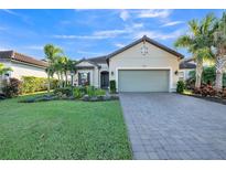 Single-story home with landscaped yard, paver driveway, and two-car garage at 12826 Sorrento Way, Bradenton, FL 34211