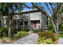 Two-story townhome with gray siding, red door, and landscaped grounds at 1479 Landings Cir # 41, Sarasota, FL 34231