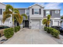 Two-story townhome with gray siding, two-car garage, and palm trees at 2471 Midnight Pearl Dr, Sarasota, FL 34240