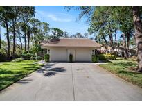 Front view of a two-car garage condo with lush landscaping and a paved driveway at 3105 Sandleheath # 1, Sarasota, FL 34235