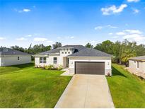 New construction home with a two-car garage and landscaped lawn at 3397 Dryden St, North Port, FL 34288