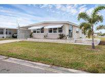 Single-wide manufactured home with carport and landscaped lawn at 1211 45Th E Ave, Ellenton, FL 34222