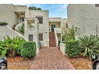 Exterior of condo building with brick pathway, lush landscaping, and parking at 5128 Marsh Field Ln # 129, Sarasota, FL 34235