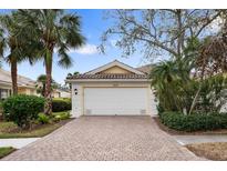 Front view of charming house with brick driveway, attached garage, and lush landscaping at 5839 Helicon Pl, Sarasota, FL 34238