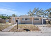 Tan house with a covered porch and a well-maintained lawn at 1518 Ewing Ave, Clearwater, FL 33756