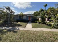 Charming single-story home with a walkway to an orange front door surrounded by lush landscaping and mature trees at 3008 7Th N Ave, St Petersburg, FL 33713