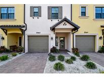 Townhome exterior showcasing gray garage doors, and well-manicured landscaping at 5560 Cannes Cir # 3-106, Sarasota, FL 34231