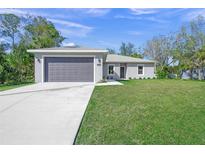 Newly constructed home with a gray exterior, attached garage, and well-manicured lawn at 5629 Crenshaw Ln, North Port, FL 34286