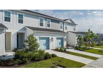 Three-unit townhome building with light gray siding, light blue garage doors, and landscaping at 8684 Canyon Creek Trl, Parrish, FL 34219