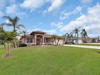 Single-story home with a red door, landscaped lawn, and palm trees at 25067 Palisade Rd, Punta Gorda, FL 33983