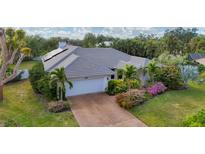 Single-story home with grey tile roof, solar panels, and lush landscaping at 5179 Flicker Field Cir, Sarasota, FL 34231