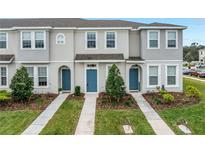 Three-unit townhome building with gray siding, blue doors, and landscaping at 6111 Fairmont Ln, Palmetto, FL 34221