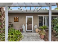 Inviting front entrance with pergola, lush landscaping, and decorative pots at 6231 Beechwood Ave, Sarasota, FL 34231