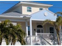 Two-story house with light yellow walls, blue accents, and a metal roof at 727 Holly Rd, Anna Maria, FL 34216