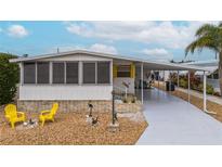 White mobile home with covered carport, yellow chairs, and landscaped yard at 2107 Palma Sola Blvd # 59, Bradenton, FL 34209