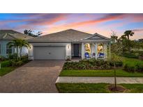 Charming house with gray siding, a two-car garage, and a landscaped front yard at 25042 Coquina Ridge Way, Englewood, FL 34223