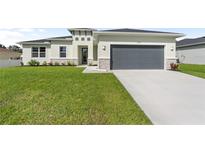 Single-story home with gray garage door and well-manicured lawn at 3425 Dryden St, North Port, FL 34288