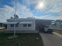 Single-wide mobile home with carport and landscaping at 5619 Bayshore Rd # 115, Palmetto, FL 34221
