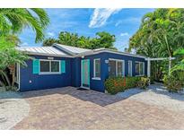 Charming blue house with teal door, surrounded by lush landscaping at 890 N Shore Dr, Anna Maria, FL 34216