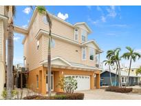 Tan three-story house with a white garage door and palm trees at 107 75Th St, Holmes Beach, FL 34217