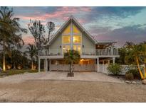 A charming two-story home with a large window and elevated deck at 315 Hammock Cir, Anna Maria, FL 34216