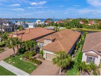 Aerial view of two-story home with tile roof, landscaping, and water views at 3904 Waypoint Ave, Osprey, FL 34229