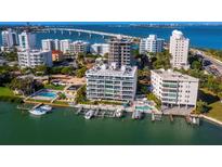 Aerial view of waterfront community with pool, boat slips, and city skyline at 650 Golden Gate Pt # 401, Sarasota, FL 34236