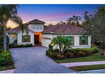 Luxury home with brick driveway, palm trees, and landscaped yard at 7504 Windy Hill Cv, Lakewood Ranch, FL 34202