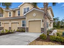 Tan two-story condo building with attached garage and landscaping at 8150 Enclave Way # 104, Sarasota, FL 34243