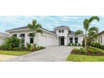 Beautiful home featuring white stucco, black window awnings, two-car garage, paved driveway and manicured landscaping at 8376 Sea Glass Ct, Sarasota, FL 34240