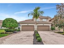 Two story townhome exterior, featuring a double-car garage and landscaped walkway at 8402 Grand Estuary Trl # 101, Bradenton, FL 34212